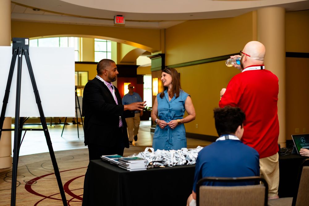 Registration table setup at a business conference with camera equipment and staging area.