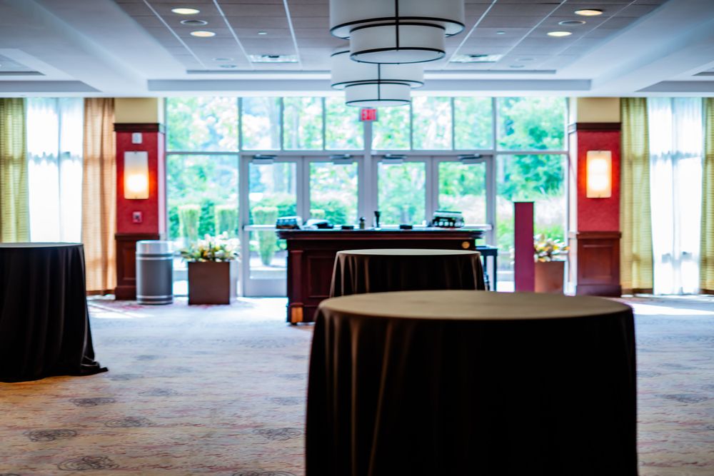 Empty conference room setup with round tables and large windows letting in natural light.