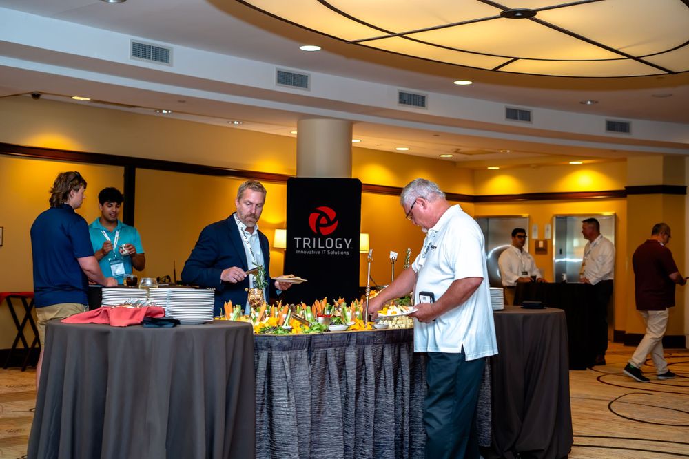 Attendees browse food and refreshments at a catered conference buffet table.