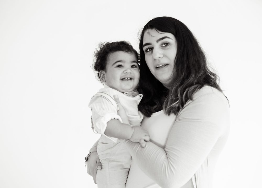 Black and white studio portrait of parent and child in tender moment.