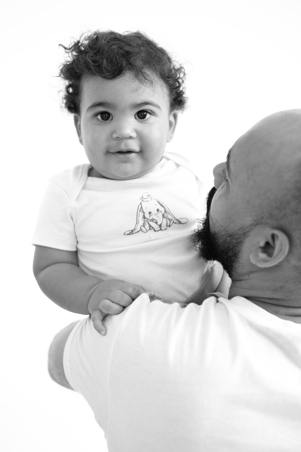 Close-up black and white portrait of parent holding smiling baby.