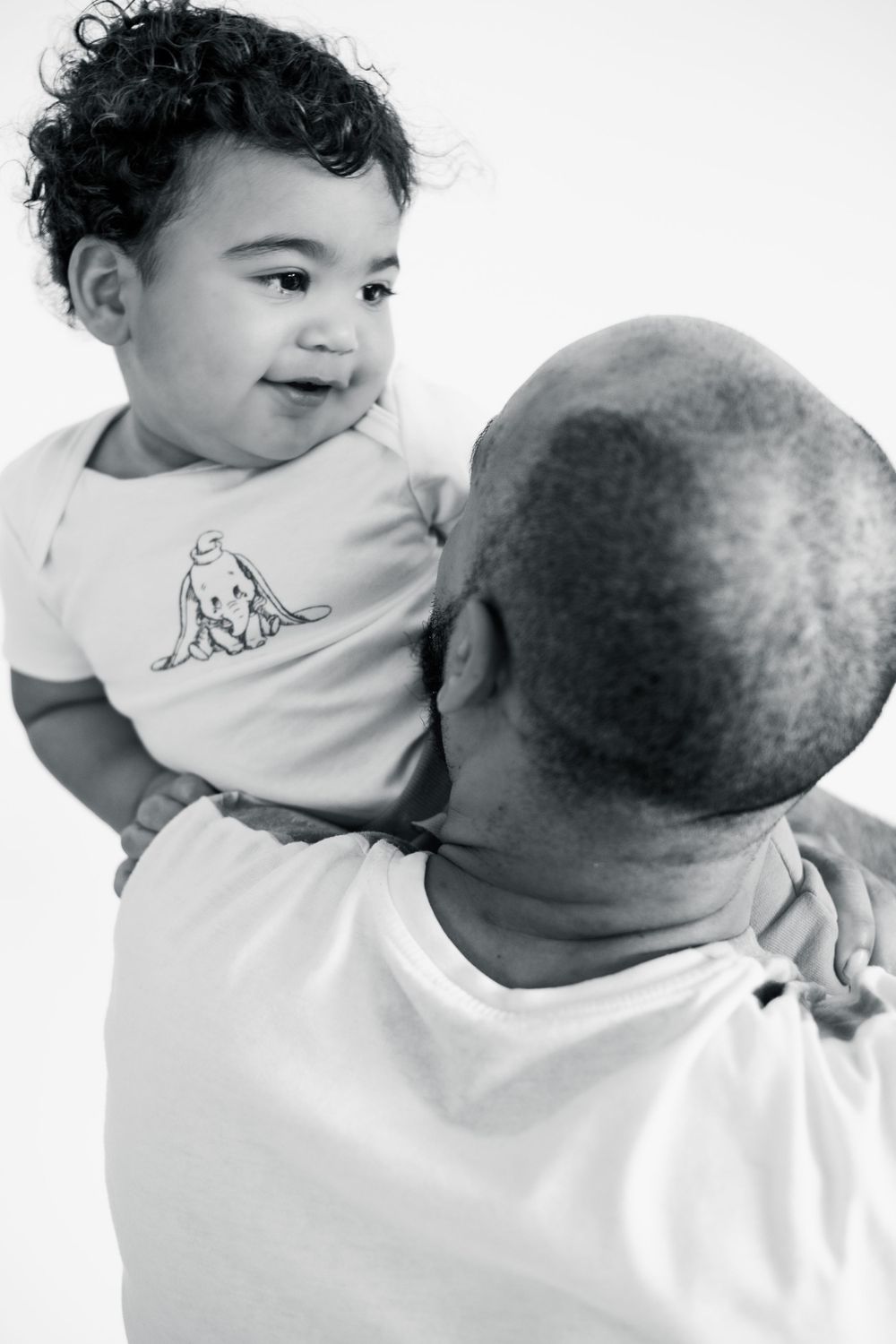 A sweet moment captured in black and white of a toddler being held up by an adult.