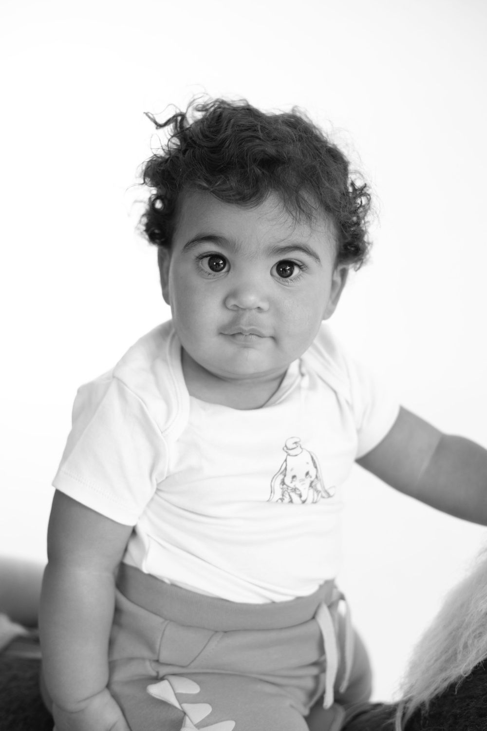Black and white portrait of a toddler wearing a white t-shirt with curly hair.