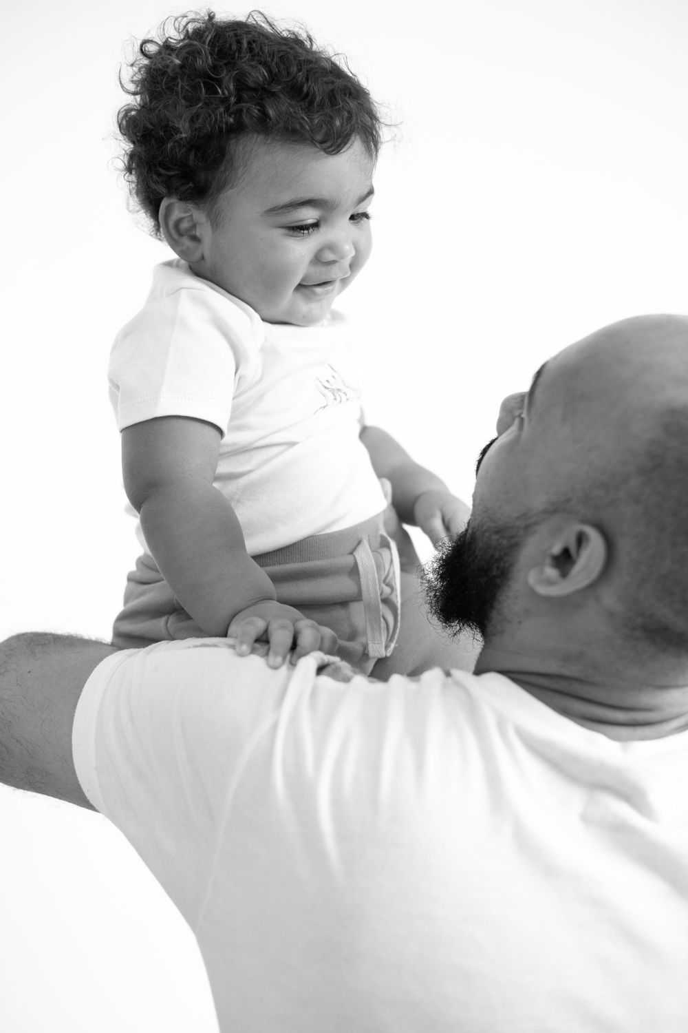 A candid black and white photo capturing a playful moment between adult and child.