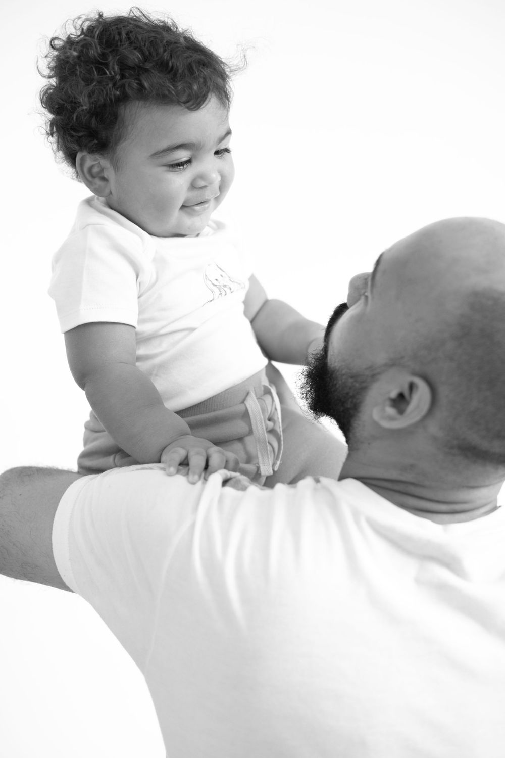 A joyful candid black and white photo showing a tender moment between a child and adult.