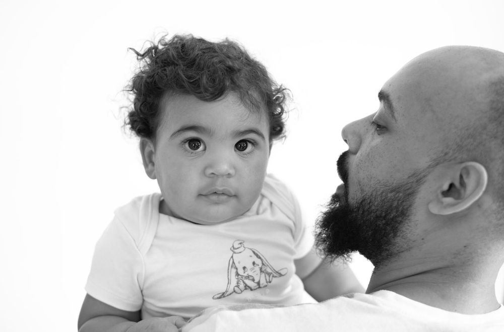 An intimate black and white portrait showing a tender moment between a child and adult.