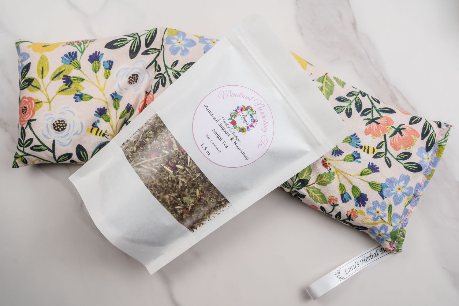 White herbal tea package with floral pattern design on fabric background.