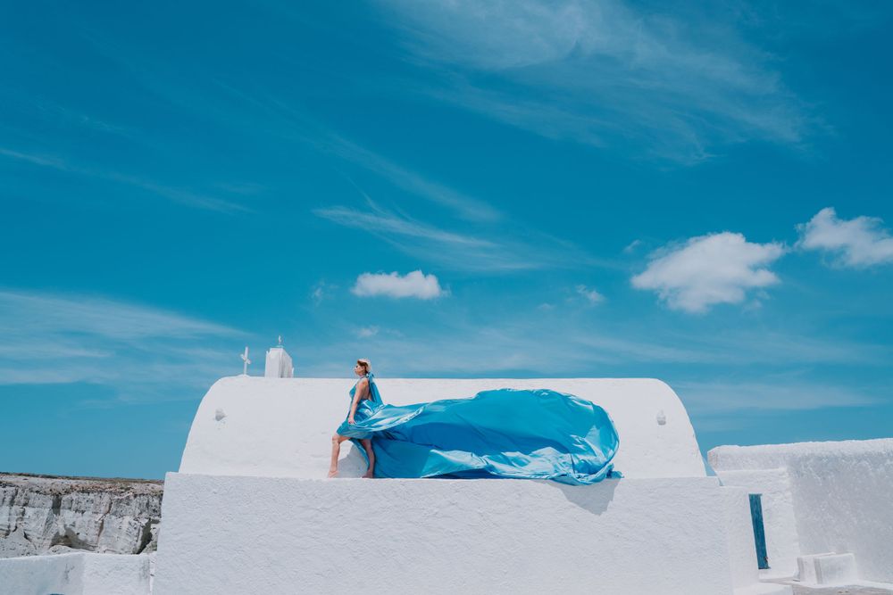 Blue flowing fabric against white architecture and clear sky in Santorini.