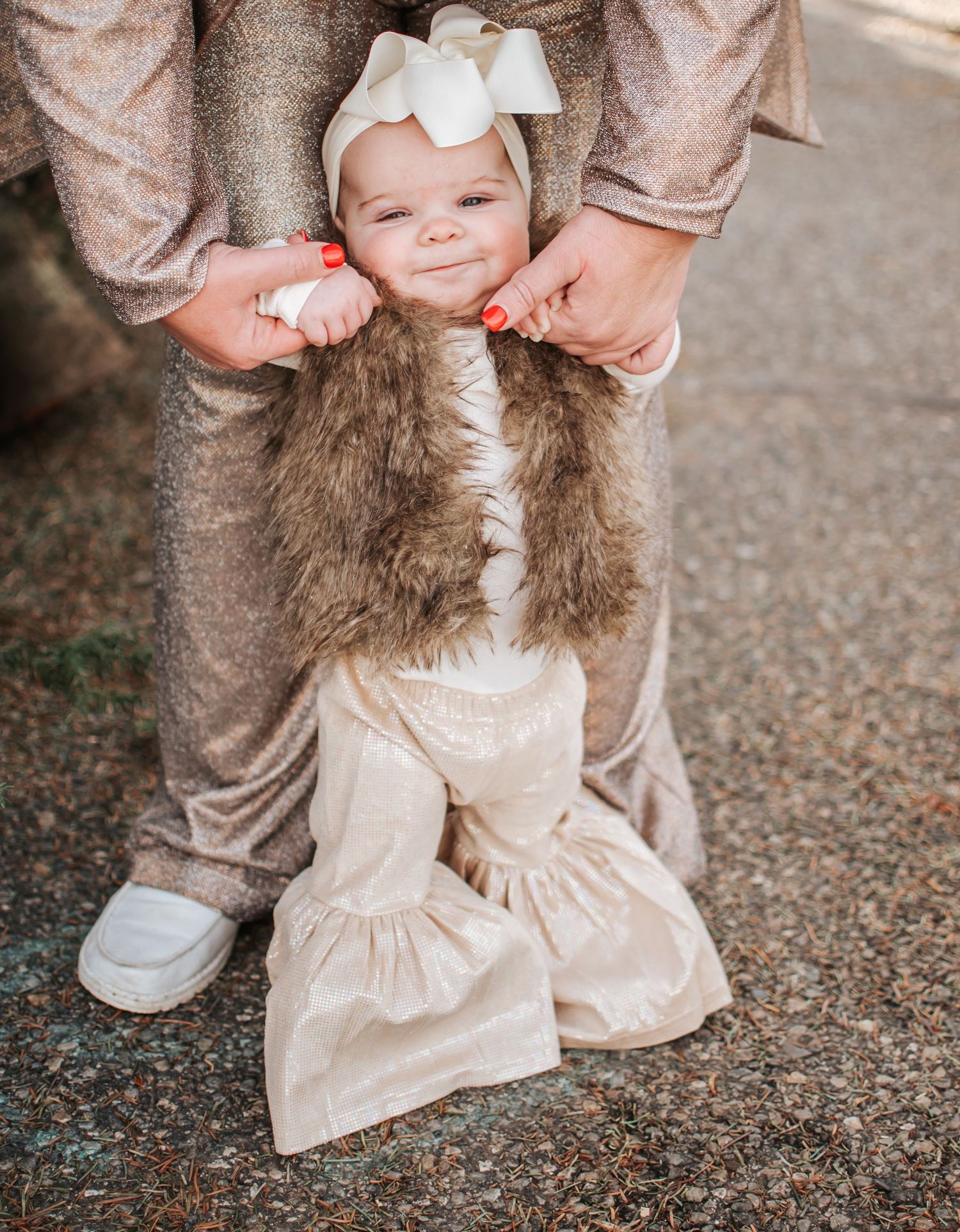 Baby in furry vest and bow headband taking first steps with parent's assistance in Pasco, Washington.