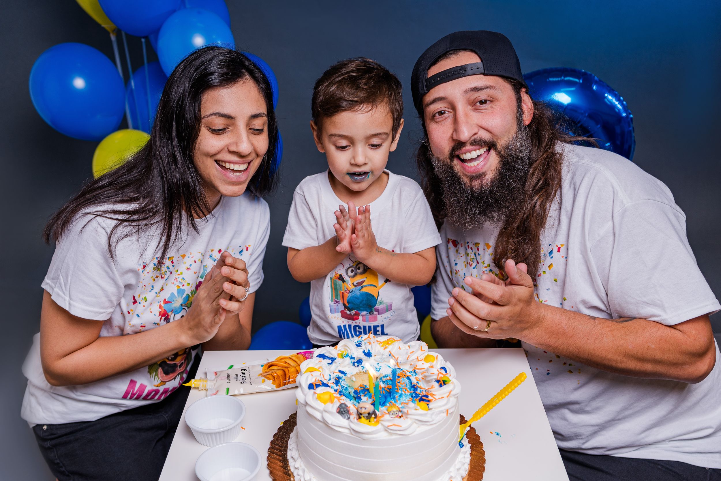 A birthday celebration with a decorated cake surrounded by blue and yellow party balloons.