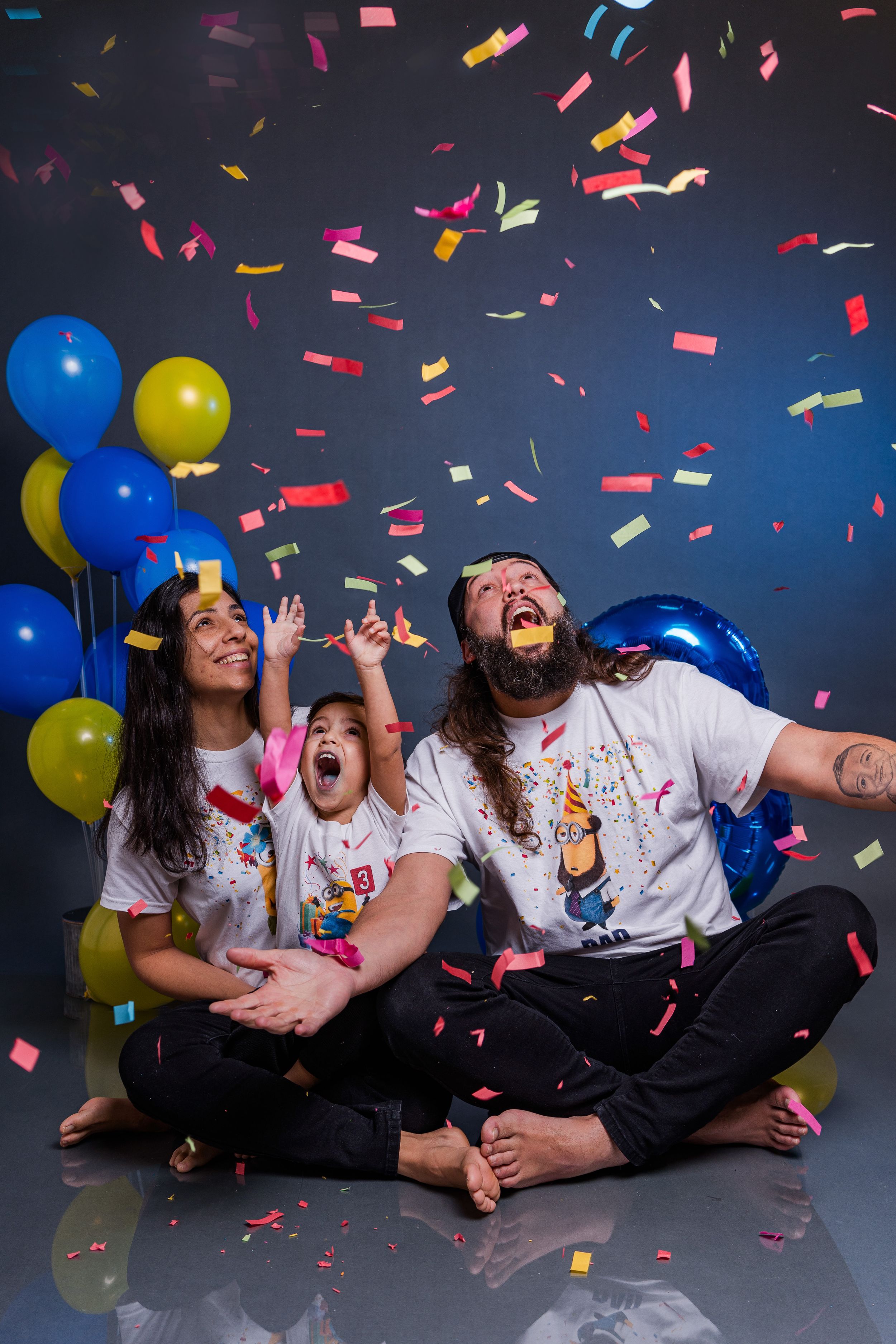 Colorful confetti rains down during a family celebration with blue and yellow balloons.