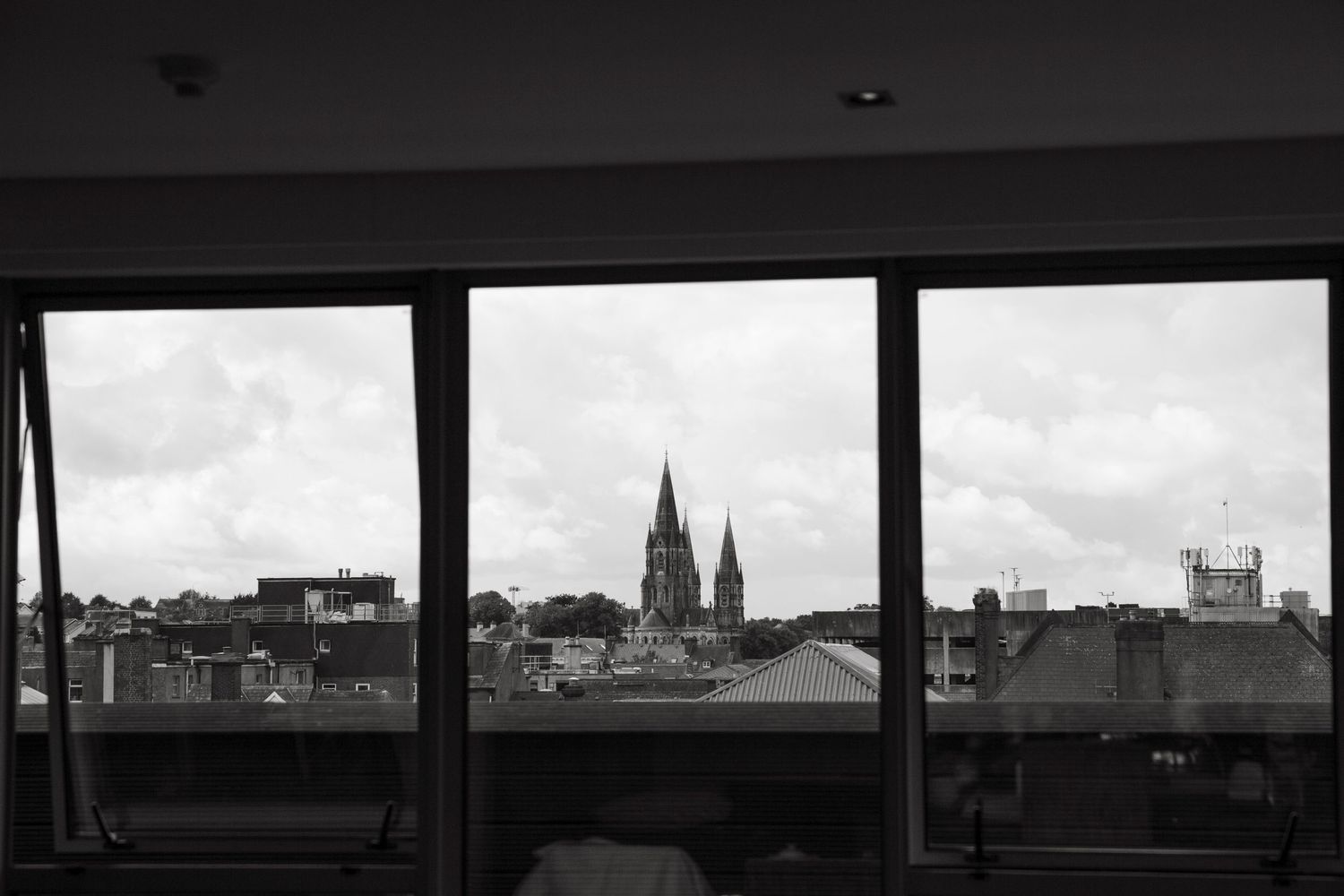 A black and white cityscape view through window panels showing church spires against the sky.
