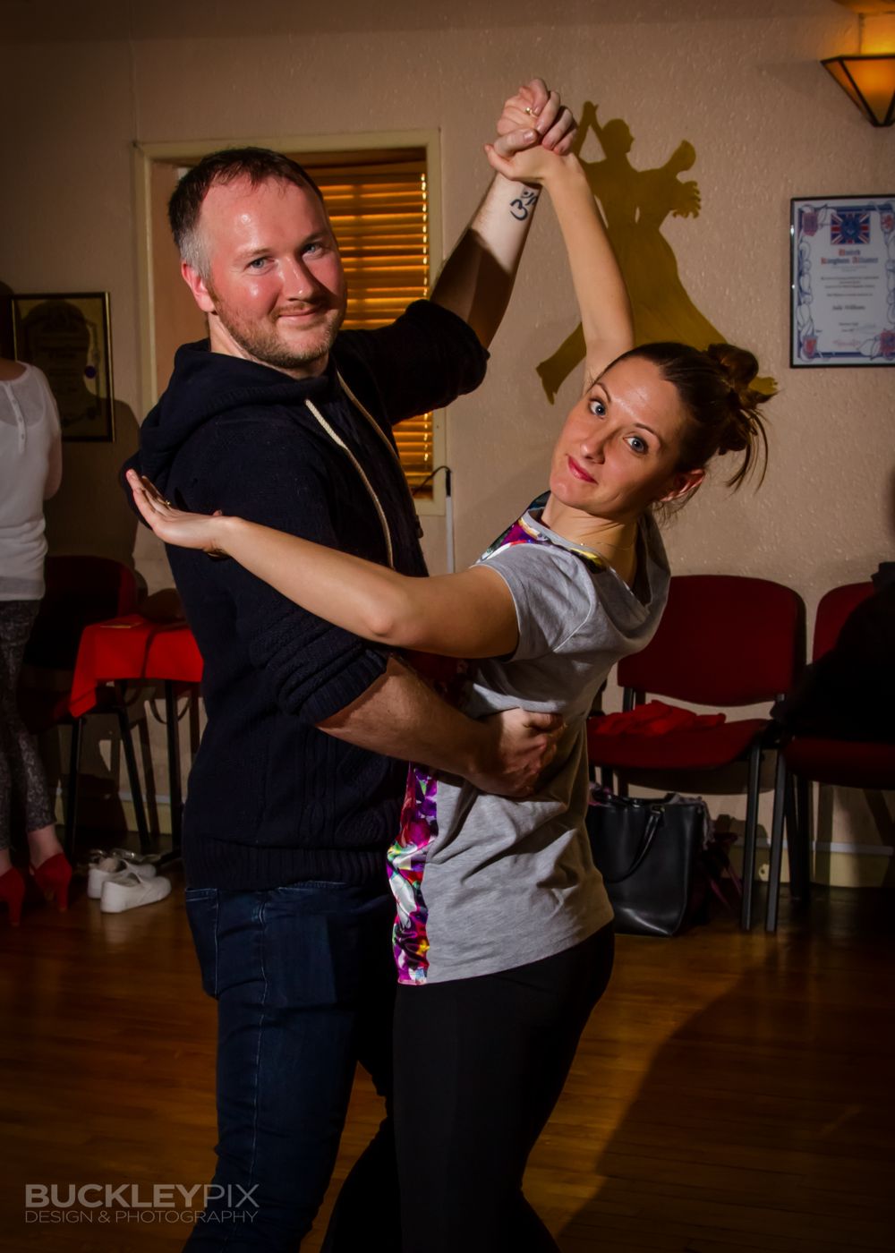 Dance partners practice their moves in a casual studio setting.