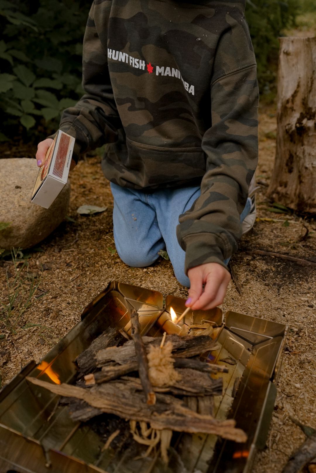 Lighting a fire in a compact camping stove with small pieces of wood.