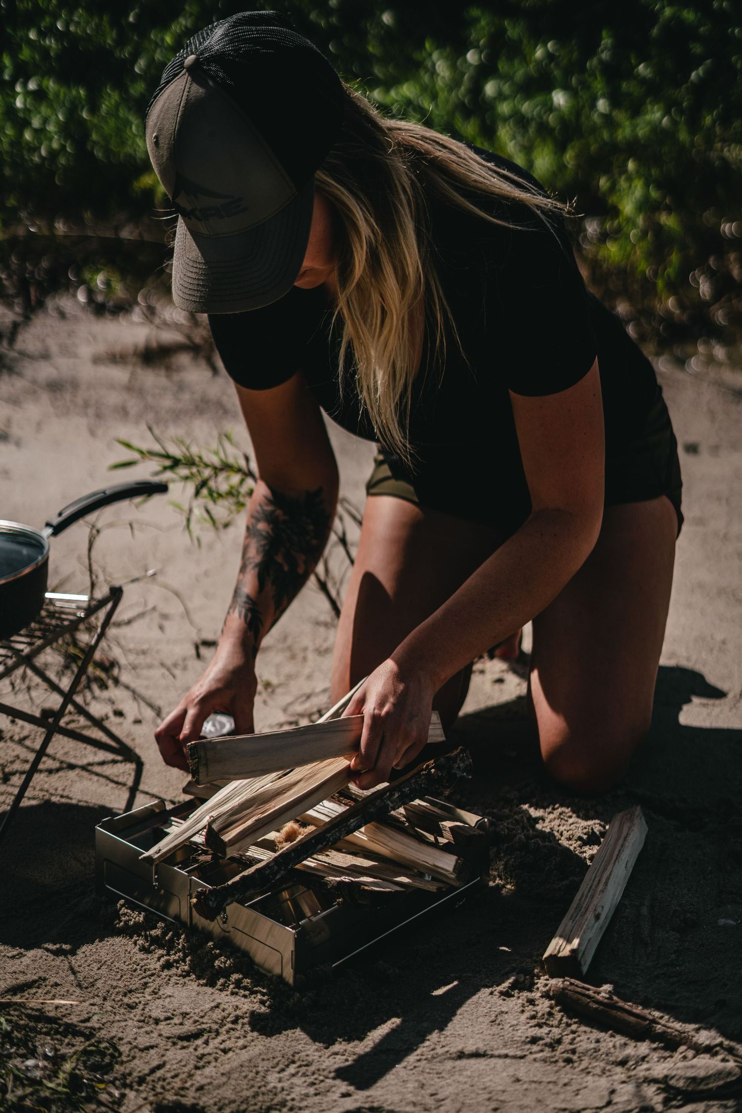 Person arranging kindling wood for campfire setup outdoors.