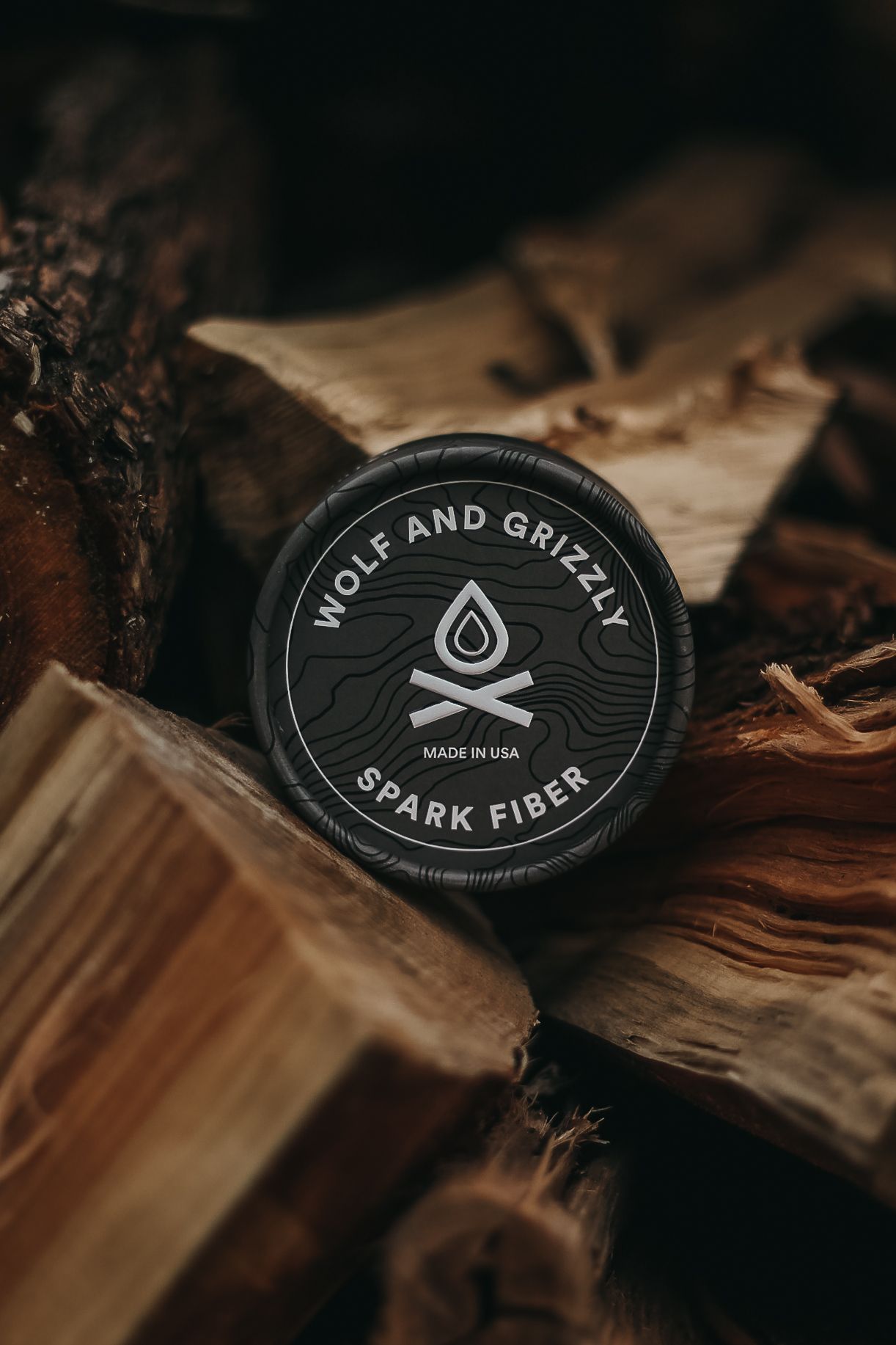 Close-up of black Wolf and Grizzly brand spark fiber patches on rustic wooden surface.