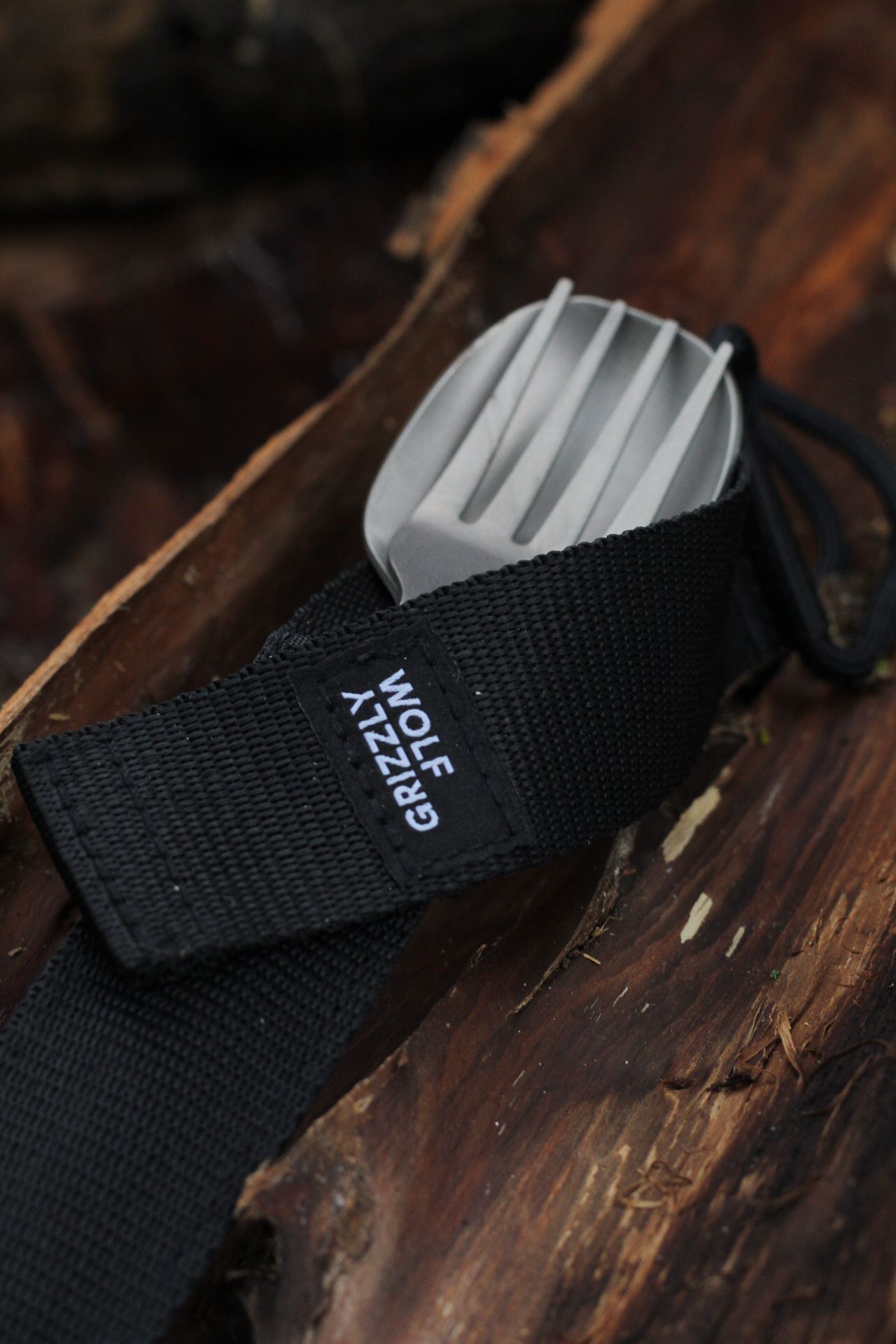 Black nylon webbing strap with white text detail on wooden surface.