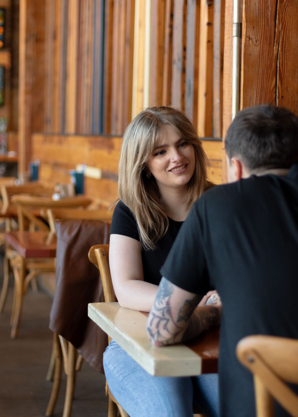 Couple sharing tender moments in a wooden interior cafe setting.