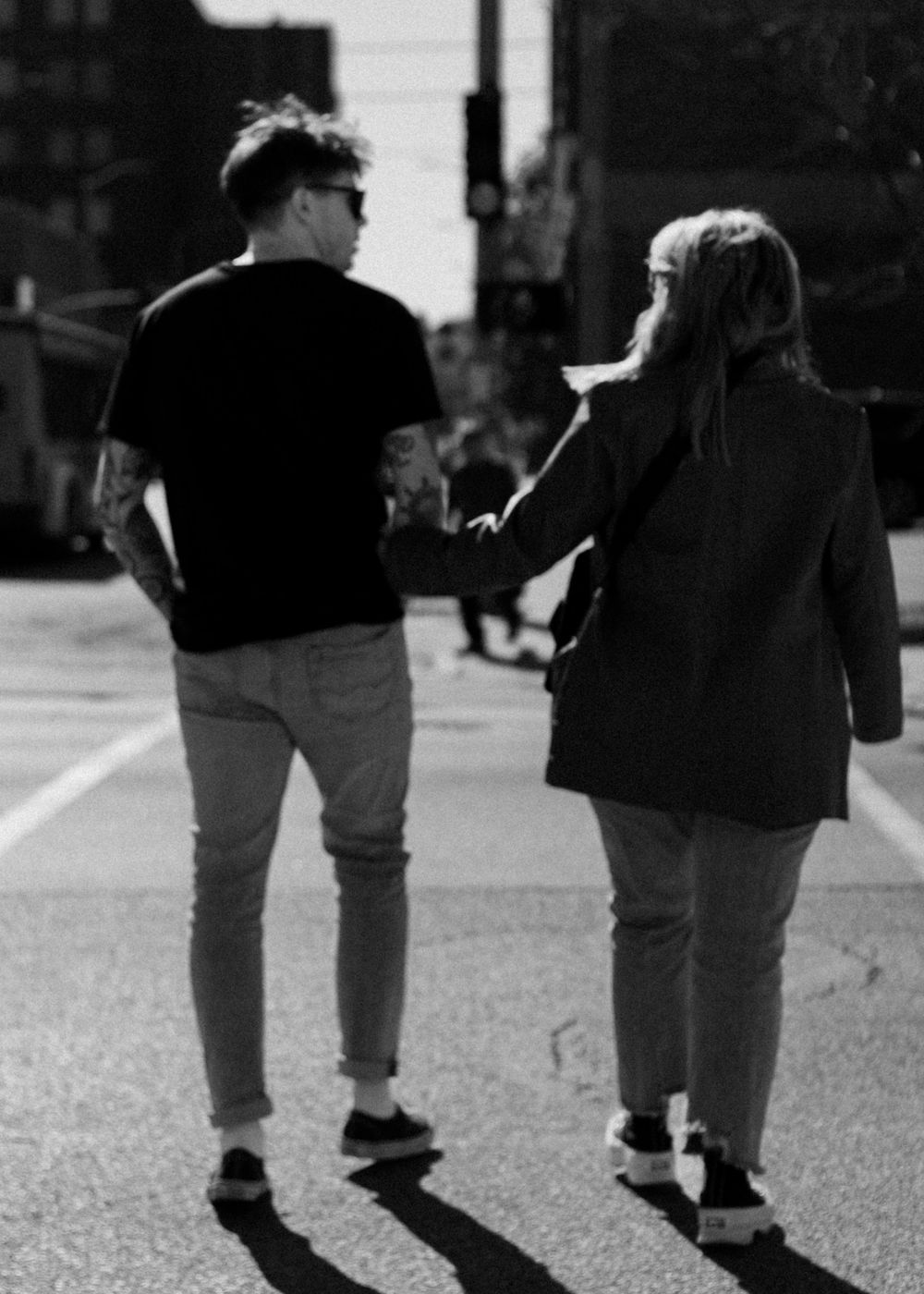 Black and white photo showing legs of a couple walking together.