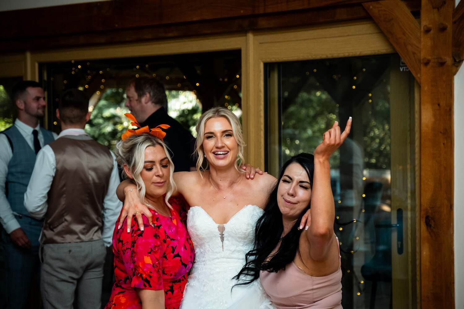 Smiling bride in between two wedding guests striking a pose