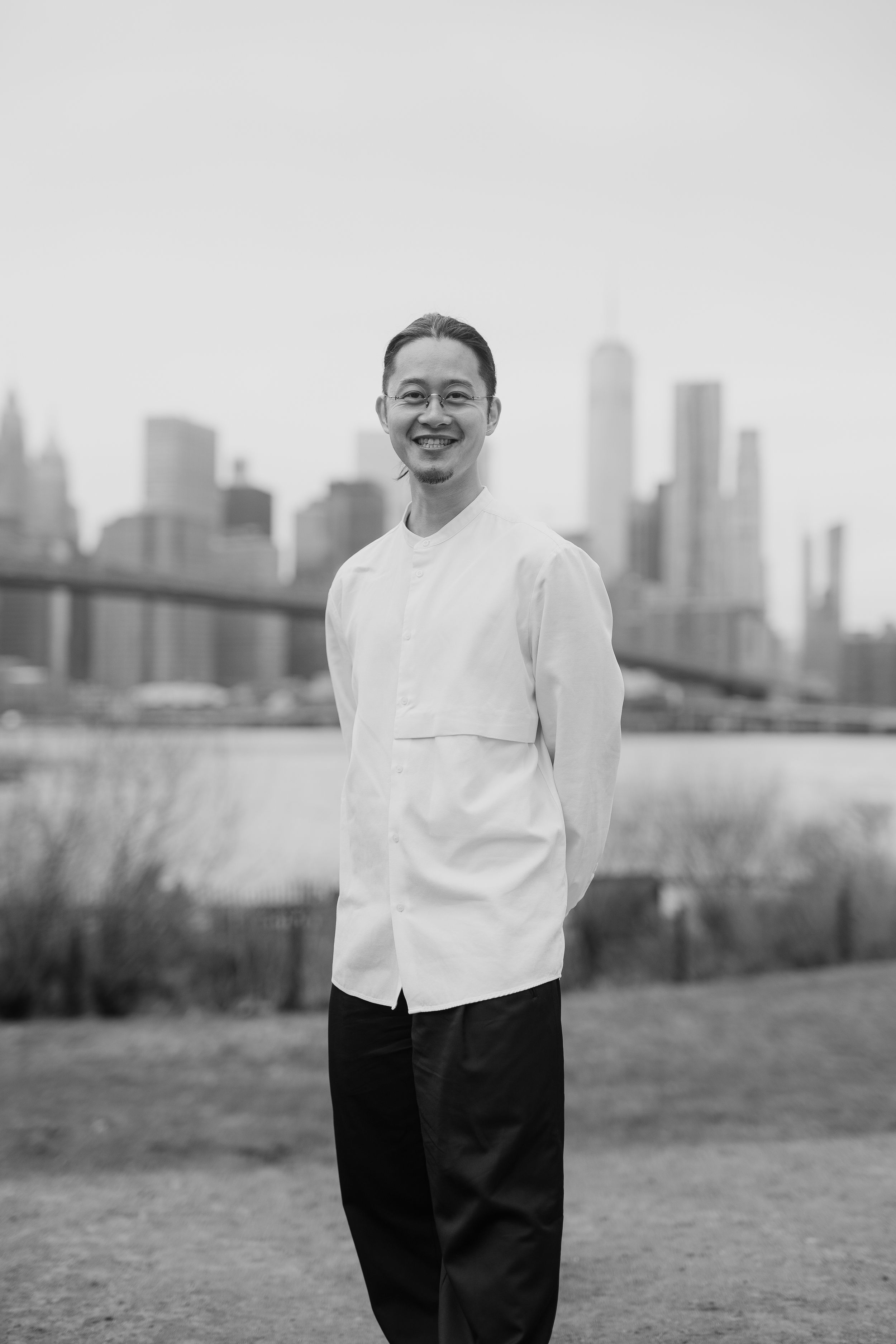 Individual in white top and dark pants posing with city skyline in background.