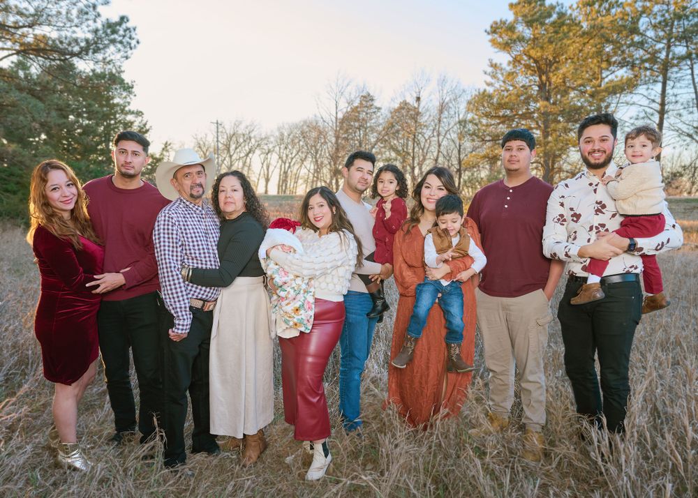 Group dressed in coordinating fall colors standing together in golden field at sunset.