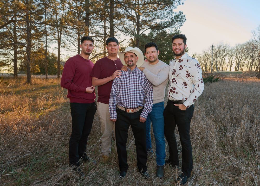 Five people in coordinating outfits pose together in outdoor field setting.