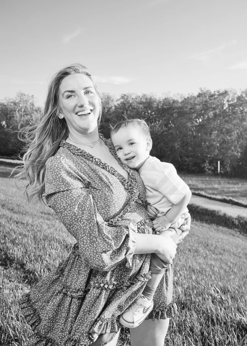 A joyful black and white portrait captured in a natural outdoor setting with tall grass.