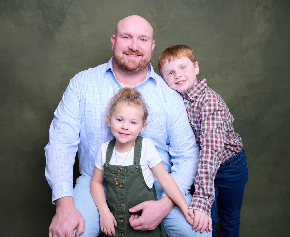 A studio portrait against a dark green backdrop.
