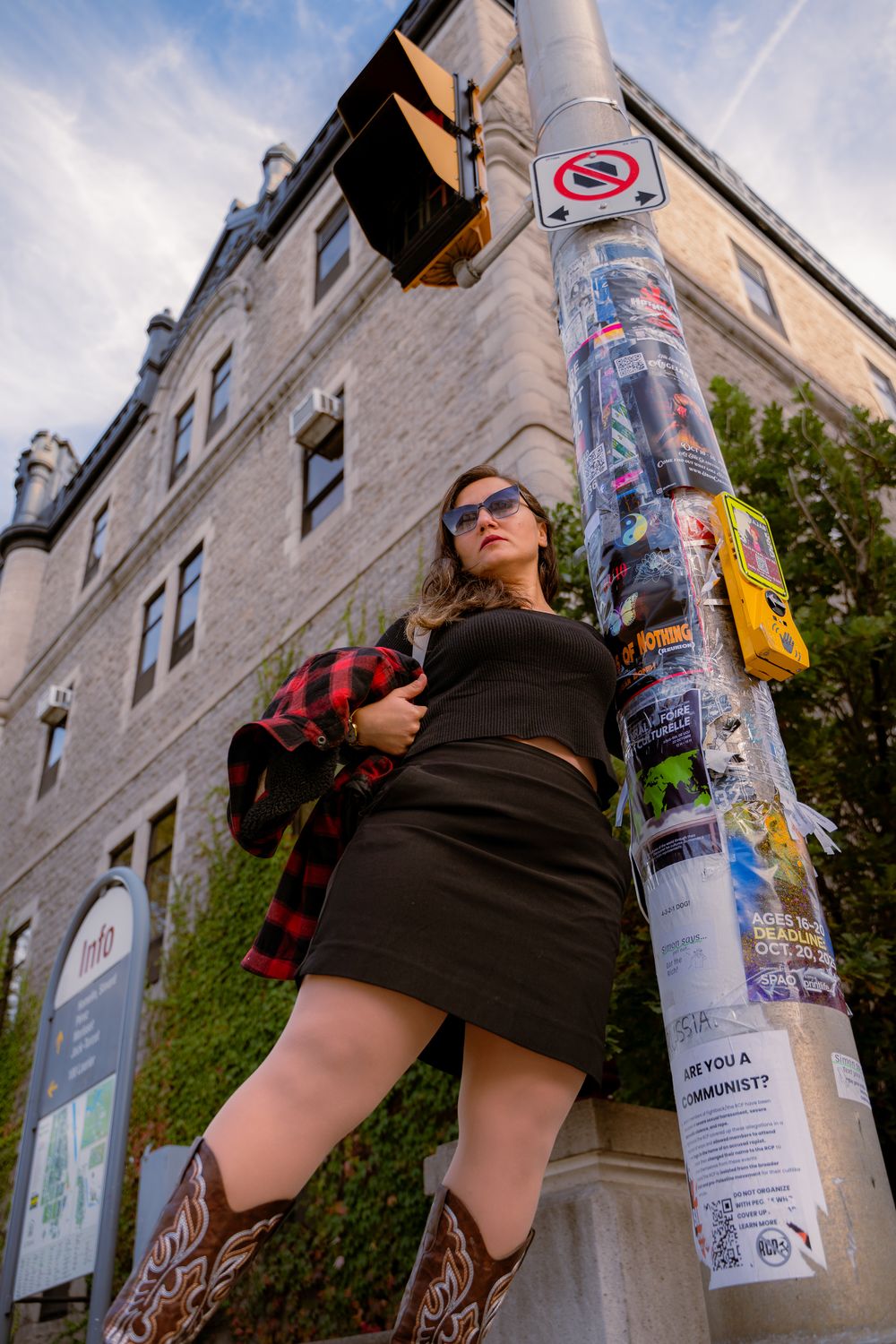 Femme en jupe noire et lunettes de soleil à côté d’un lampadaire, bâtiments en arrière-plan à Ottawa, Ontario.