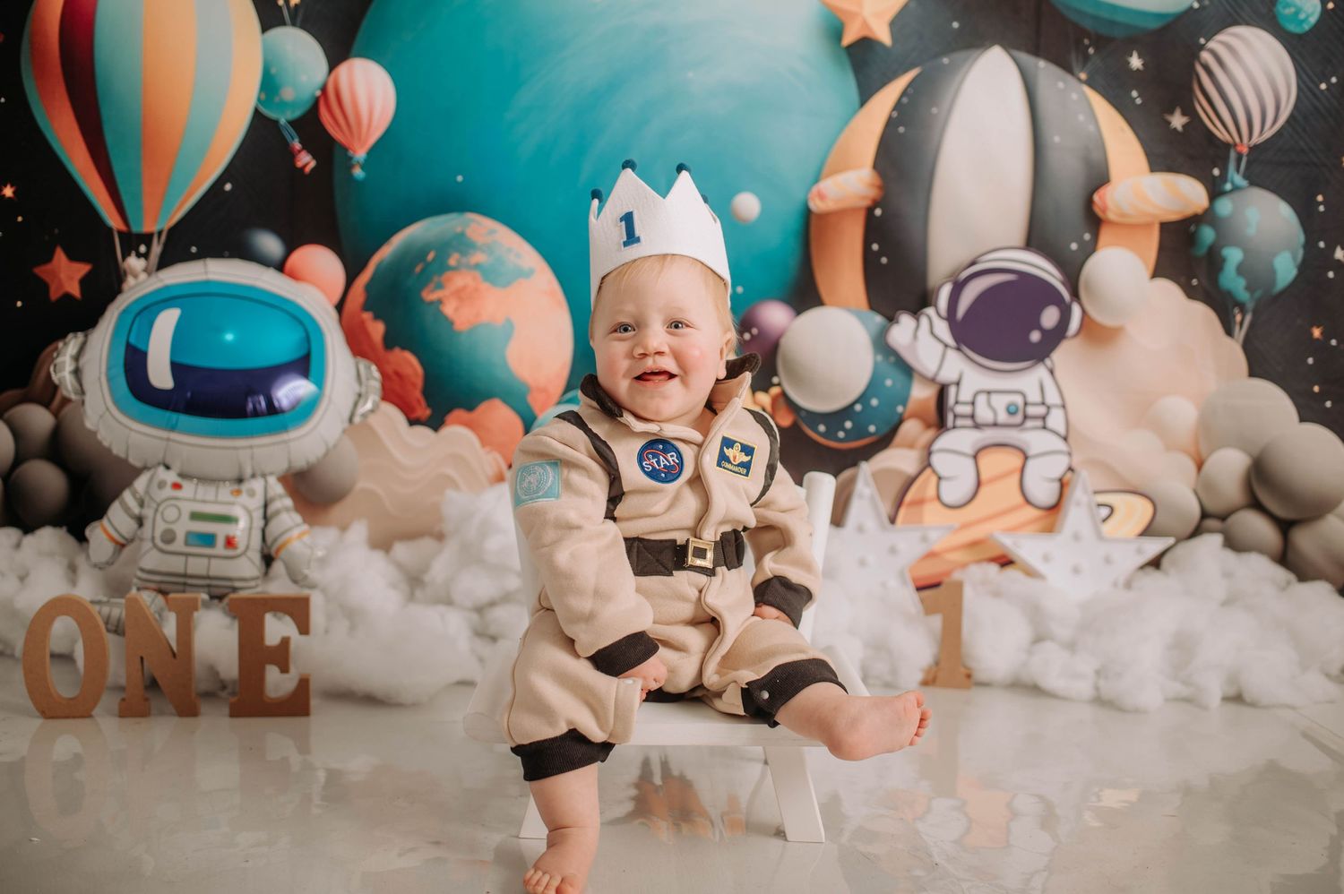 Space-themed first birthday photo with astronaut costume and stellar decorations.