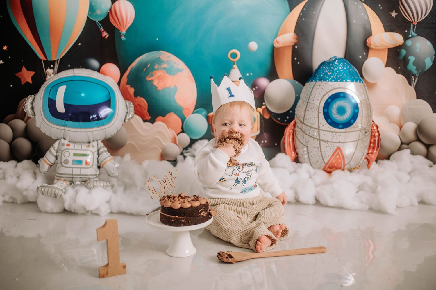 Space-themed birthday setup with astronaut decorations and cloudy backdrop.