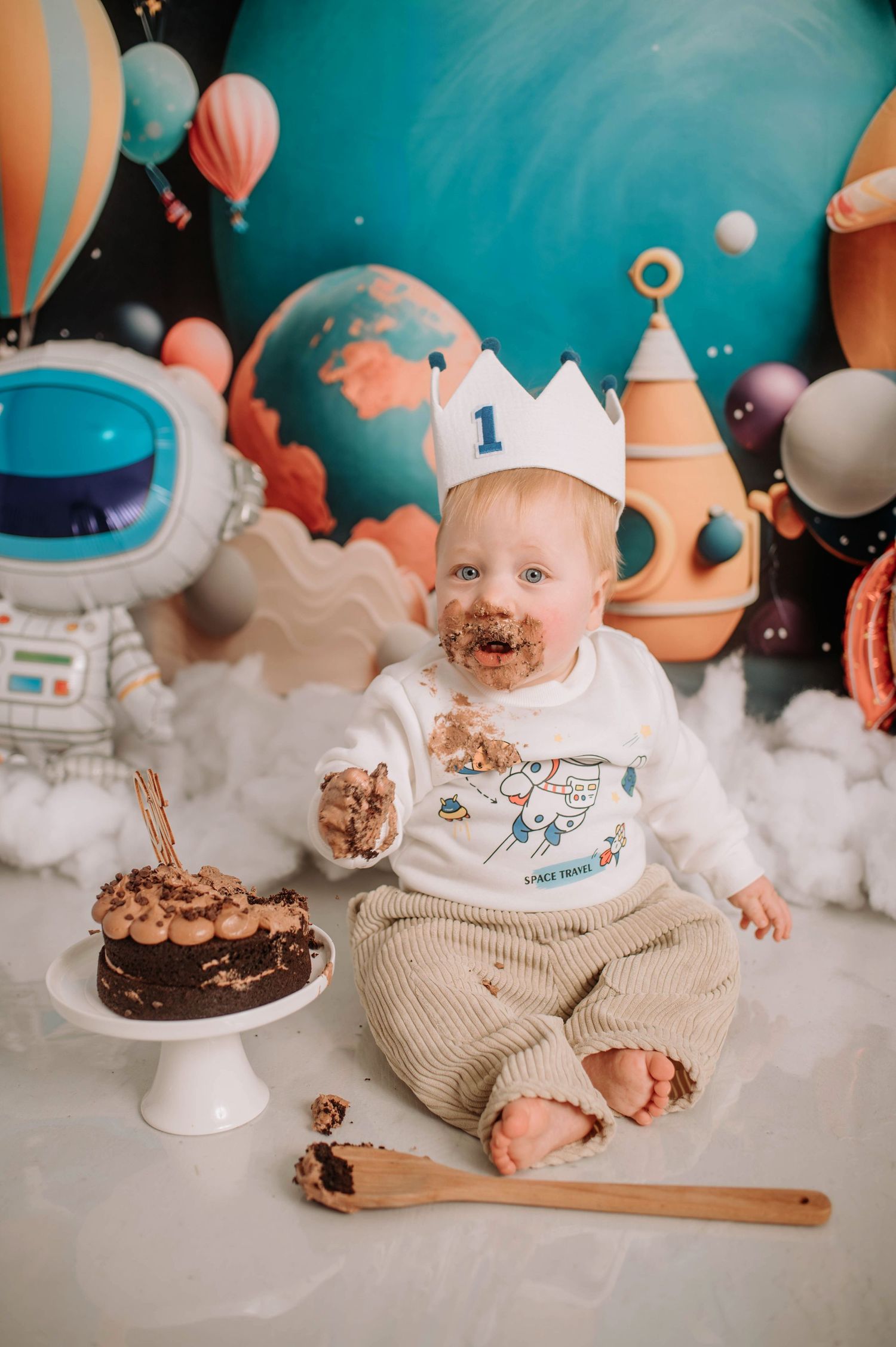 First birthday celebration with chocolate cake and astronaut-themed decor.