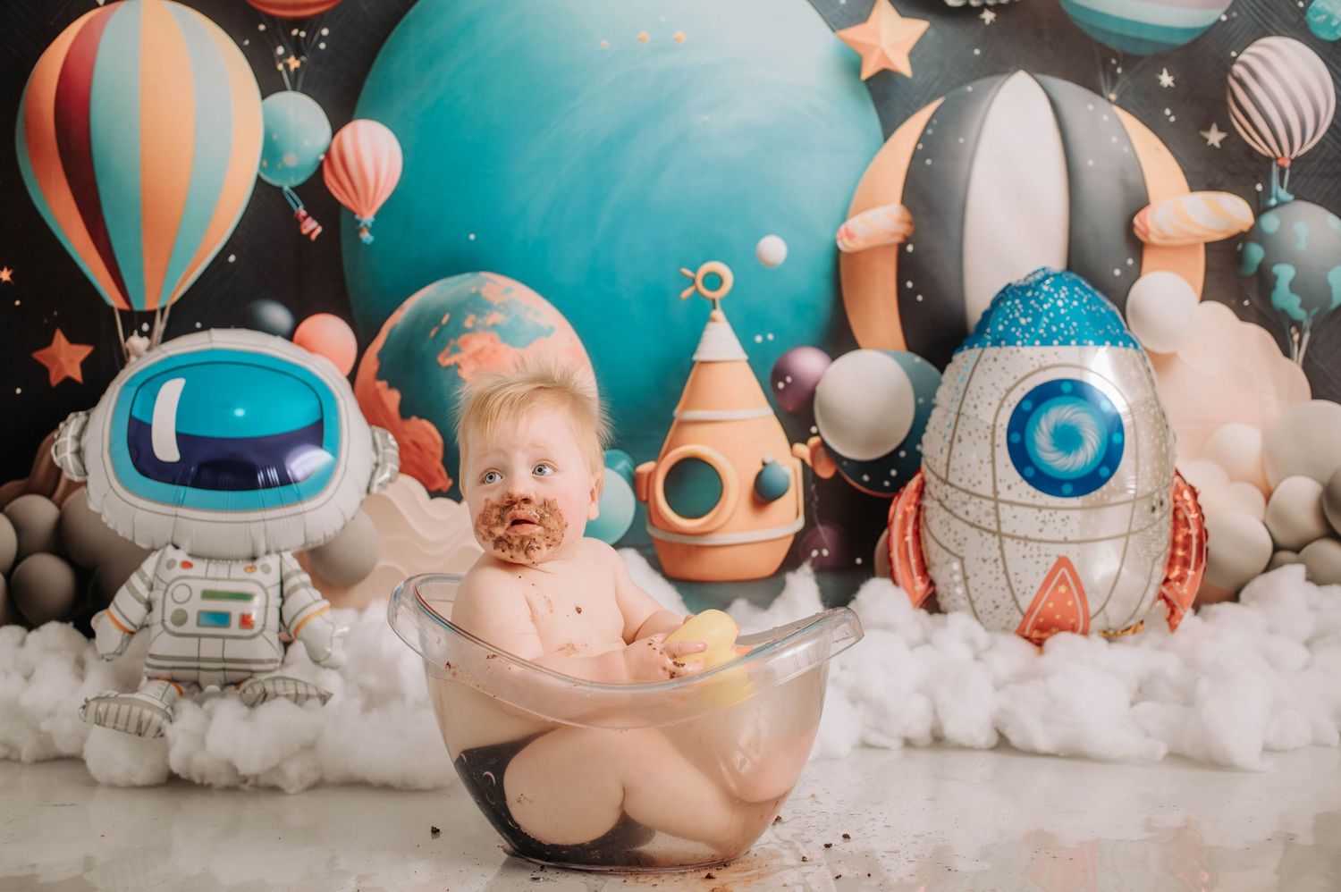 Space-themed cake smash photography with astronaut and rocket decorations.
