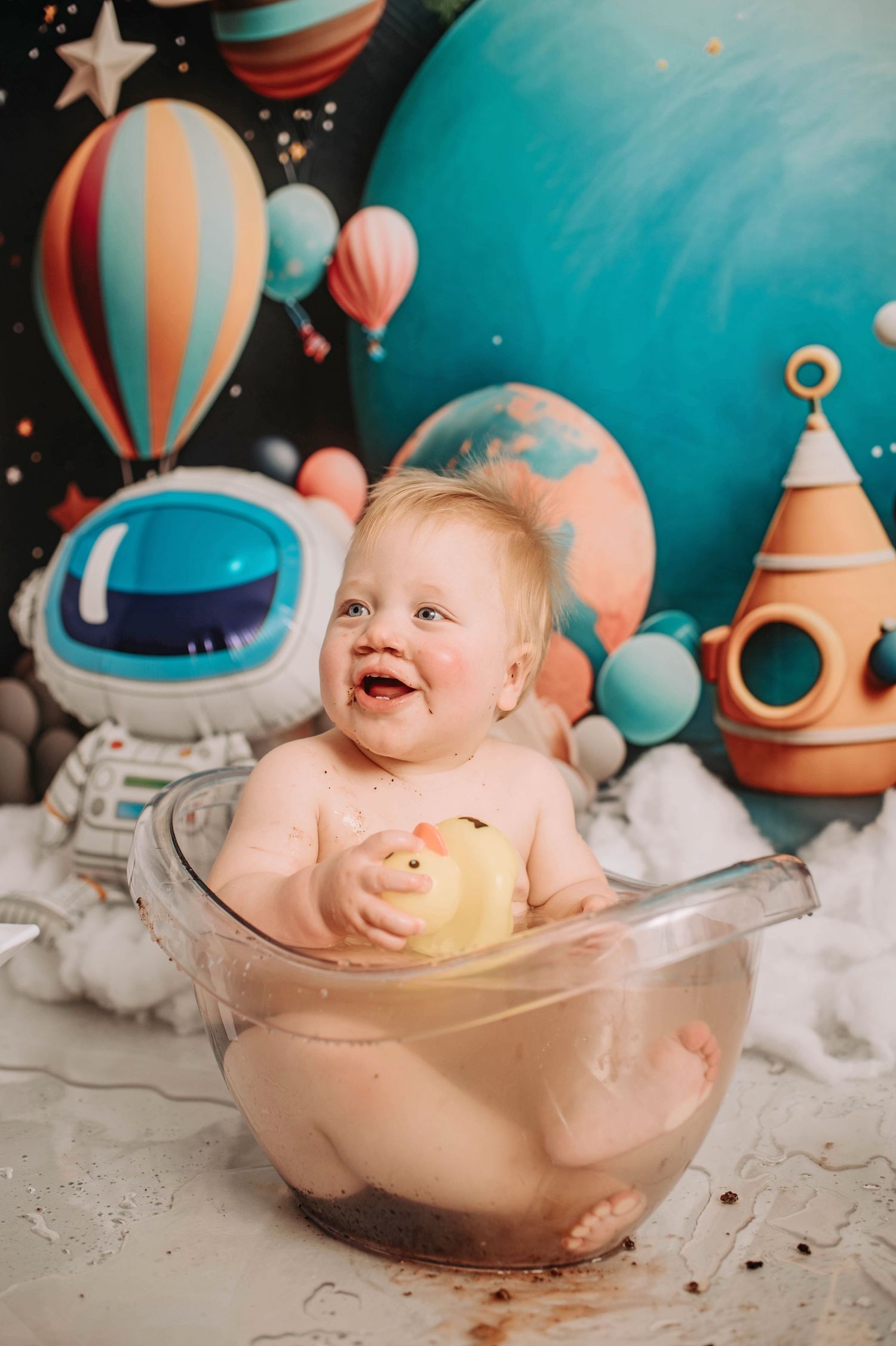 Joyful bath scene during cake smash photoshoot with space-themed backdrop.