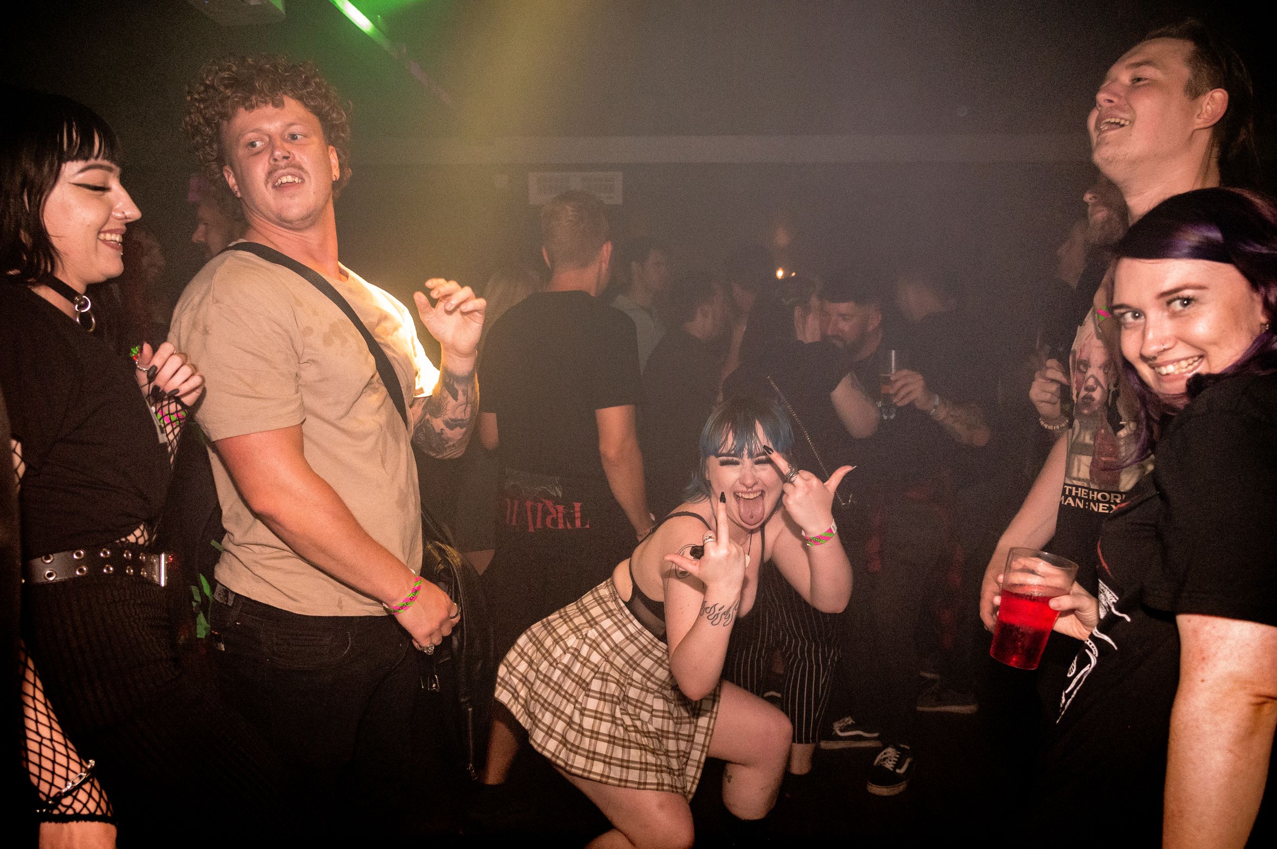 People dancing and socializing at a nightclub with green lighting effects.