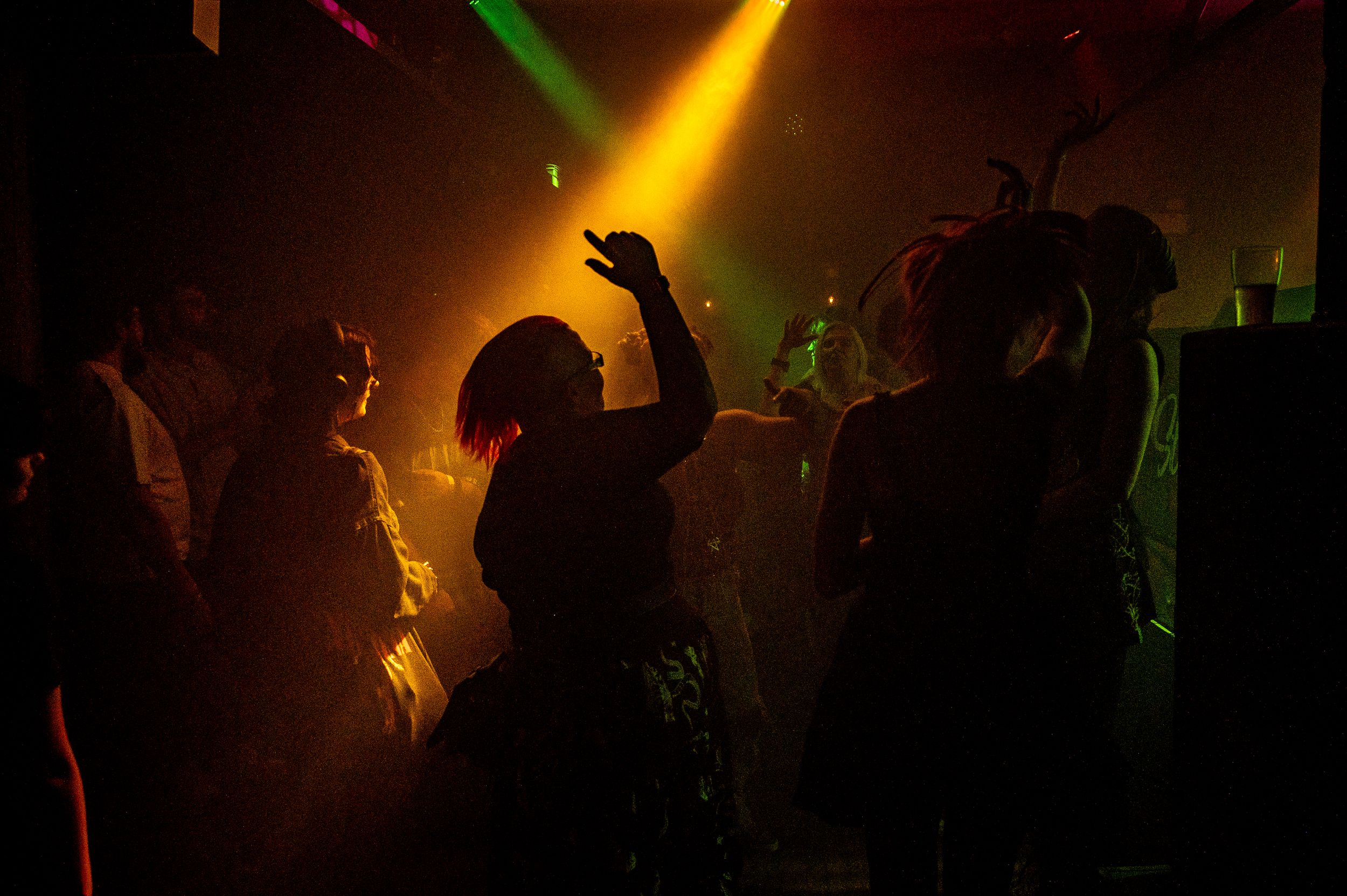 Silhouettes of dancers in nightclub with dramatic colored lighting effects.