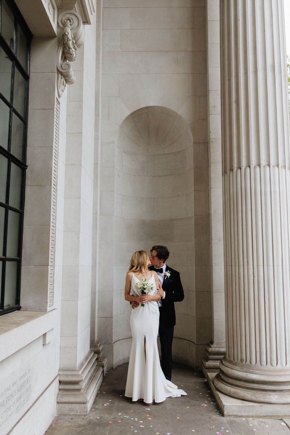 A romantic moment between newlyweds among classical white stone columns.
