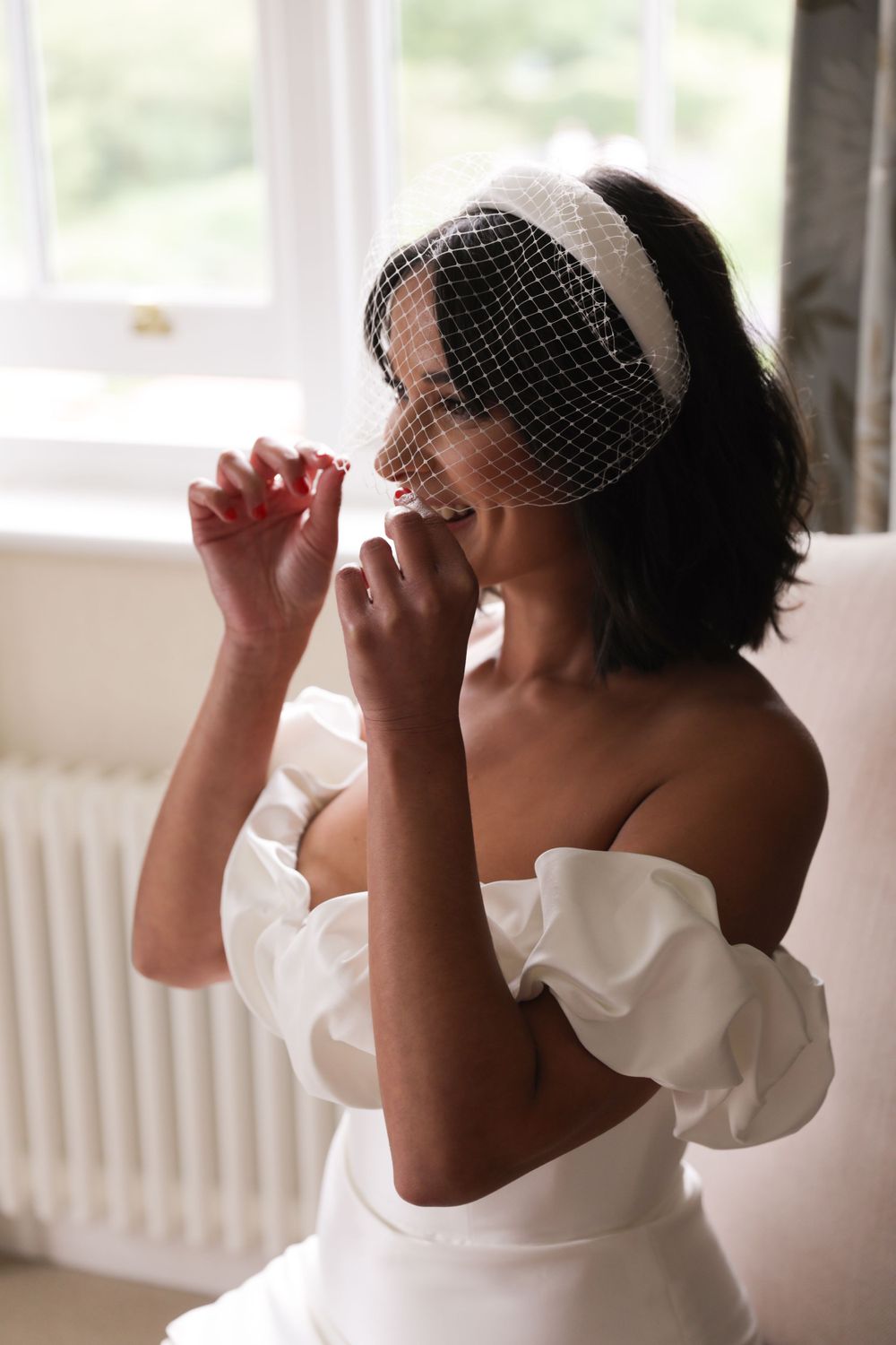 Elegant bridal portrait with vintage birdcage veil in natural window light.