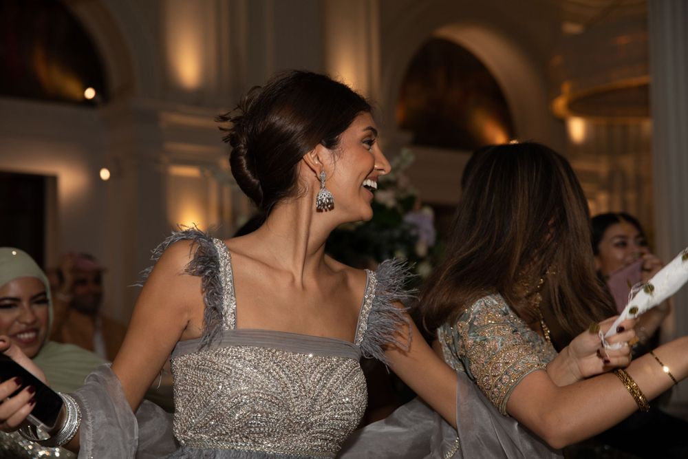 Wedding guests in sparkly dresses dancing and celebrating at an evening reception.
