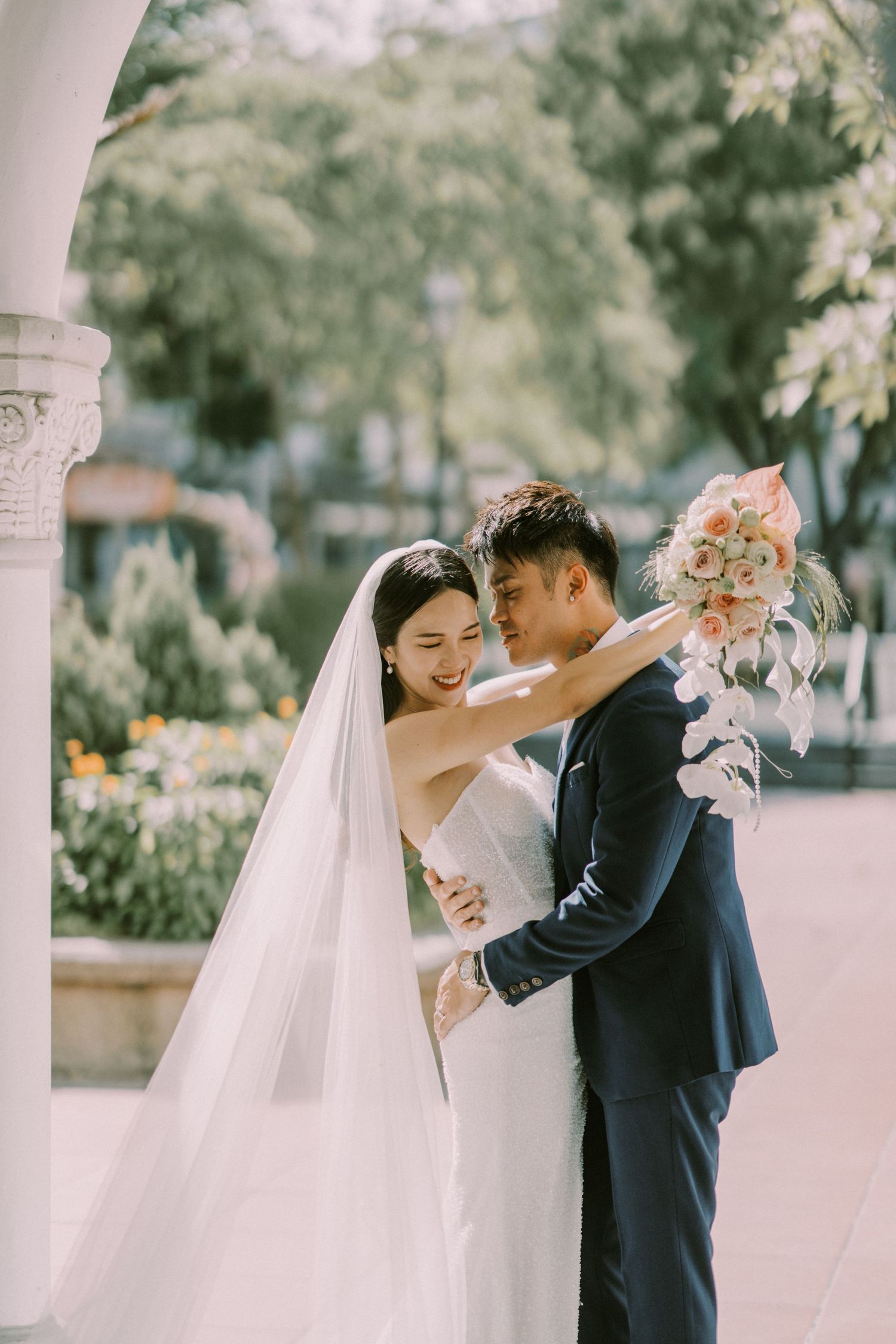 A romantic wedding couple shares tender moments under an elegant white porch during their special day.