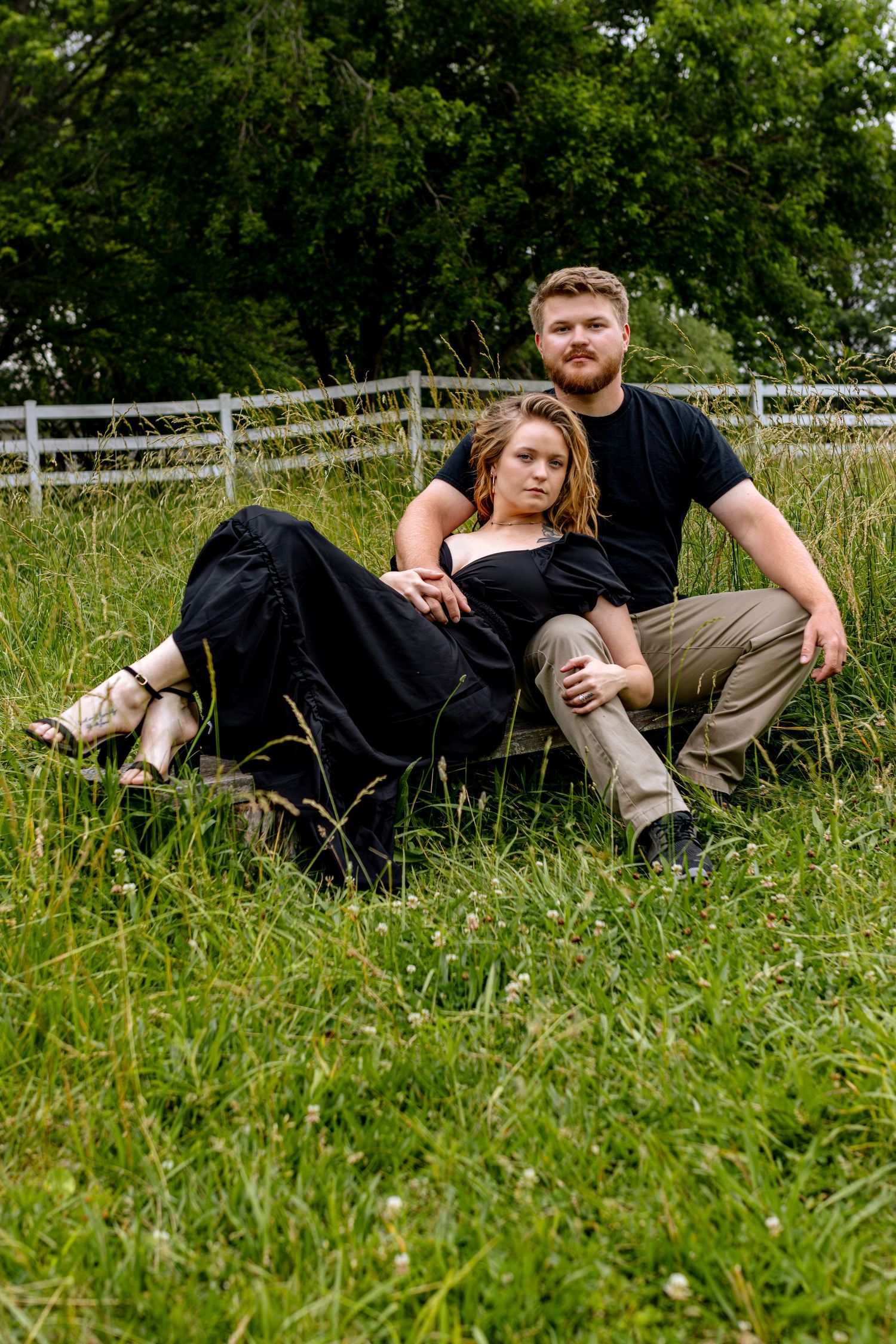 Couple laying in tall green grass during an outdoor photo session.