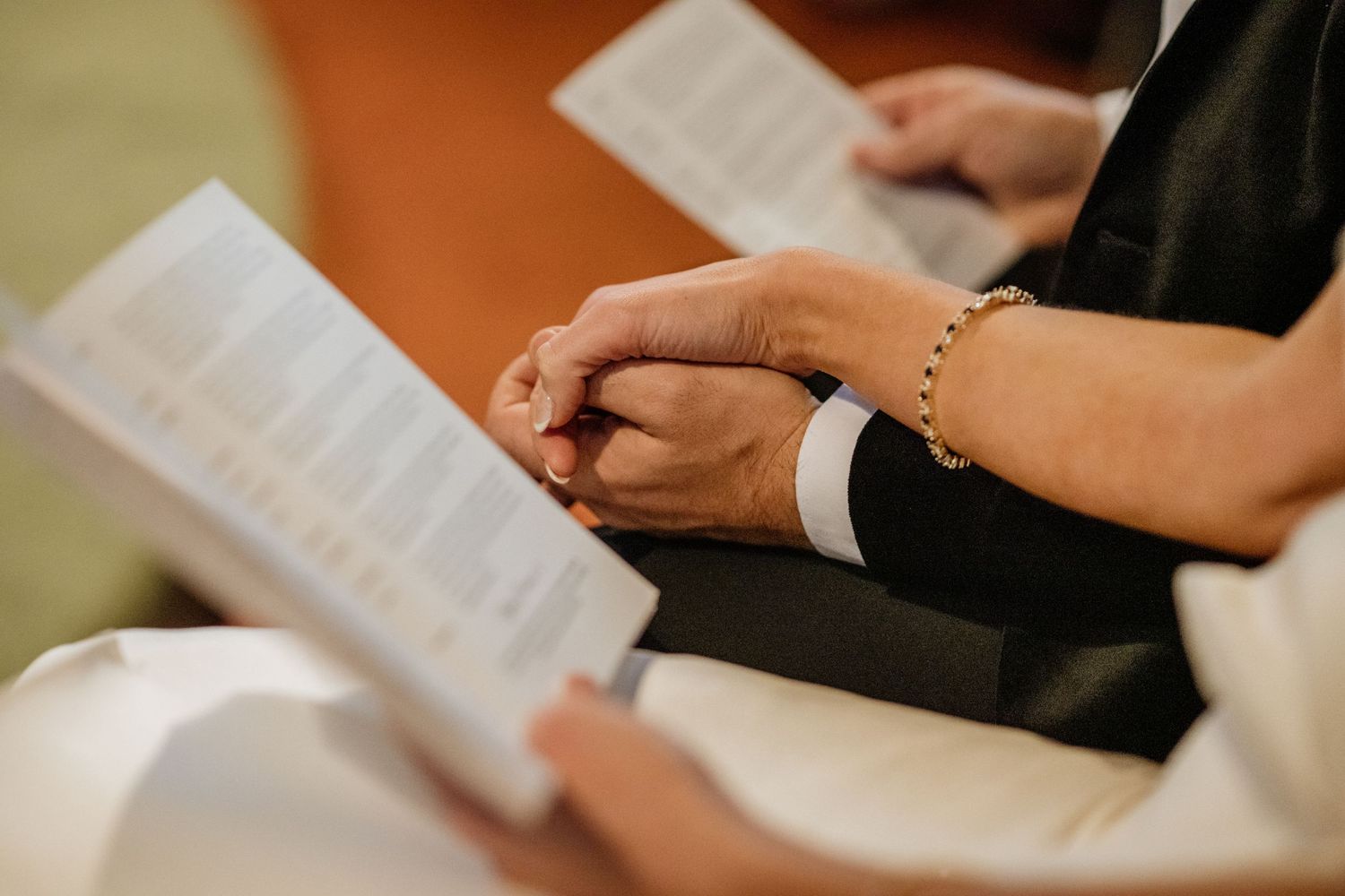 Close up of hands holding paper documents during church in county Leitrim ceremony.