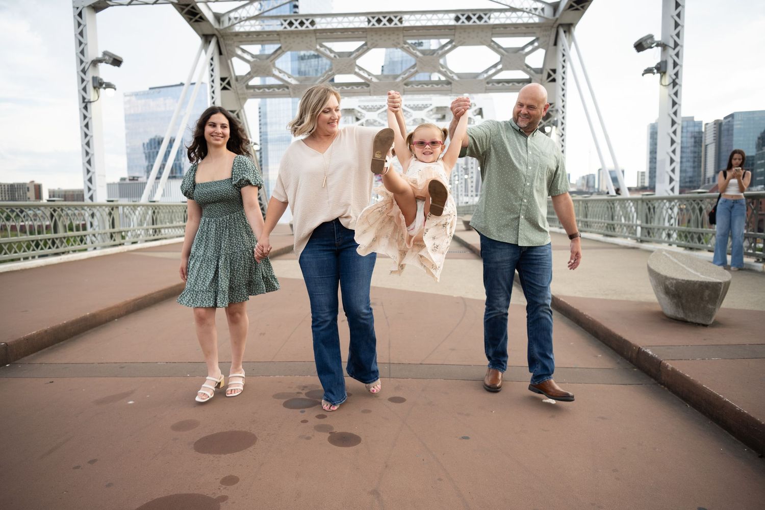 Four people dancing joyfully together on the Pedestrian Bridge in Nashville TN  in casual attire during a sunny day
