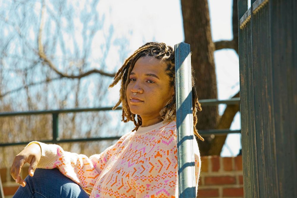 Person in pink shirt and jeans relaxing outdoors in natural sunlight on a sunny day.