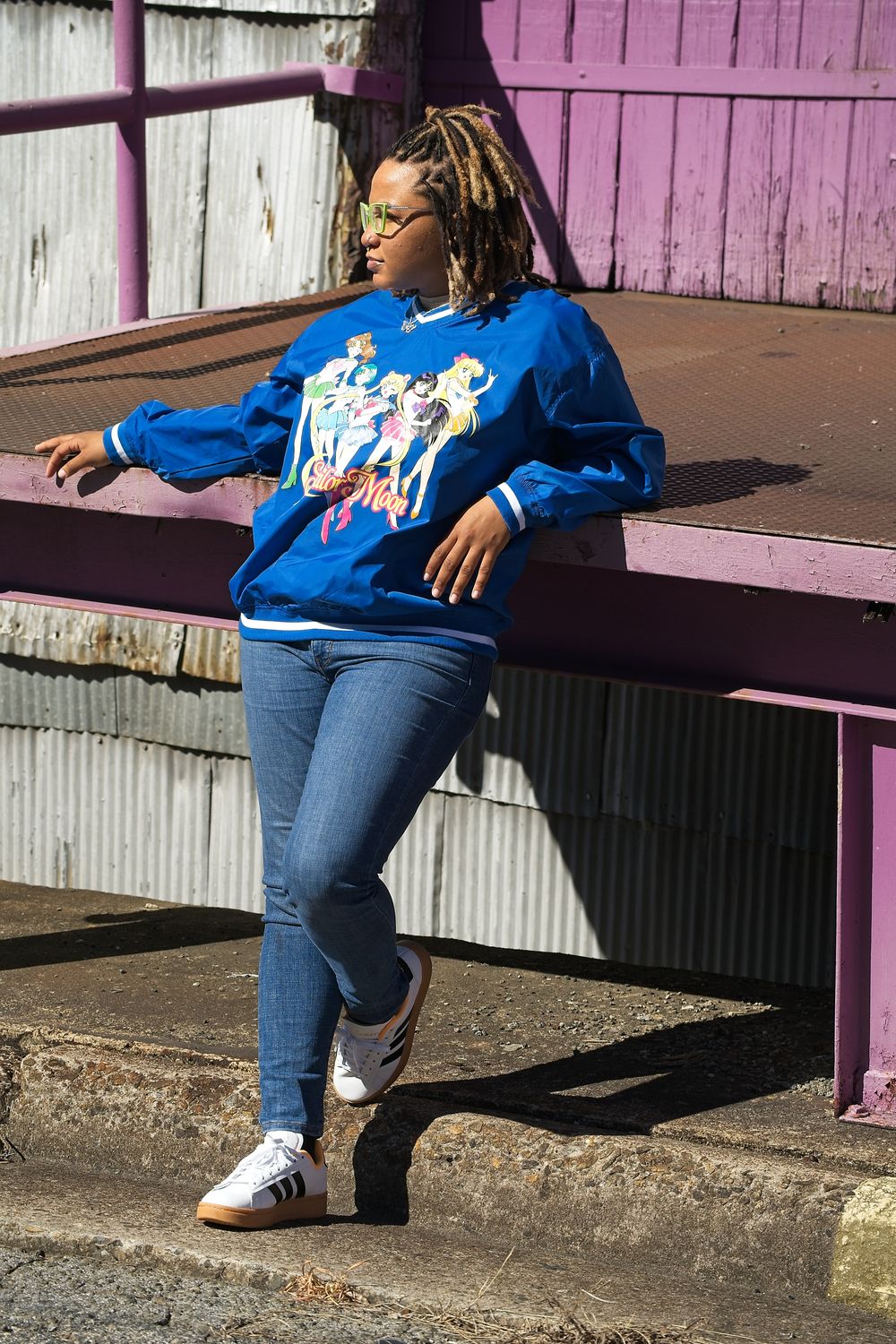 Person wearing blue sweater and jeans sits casually on purple painted steps.