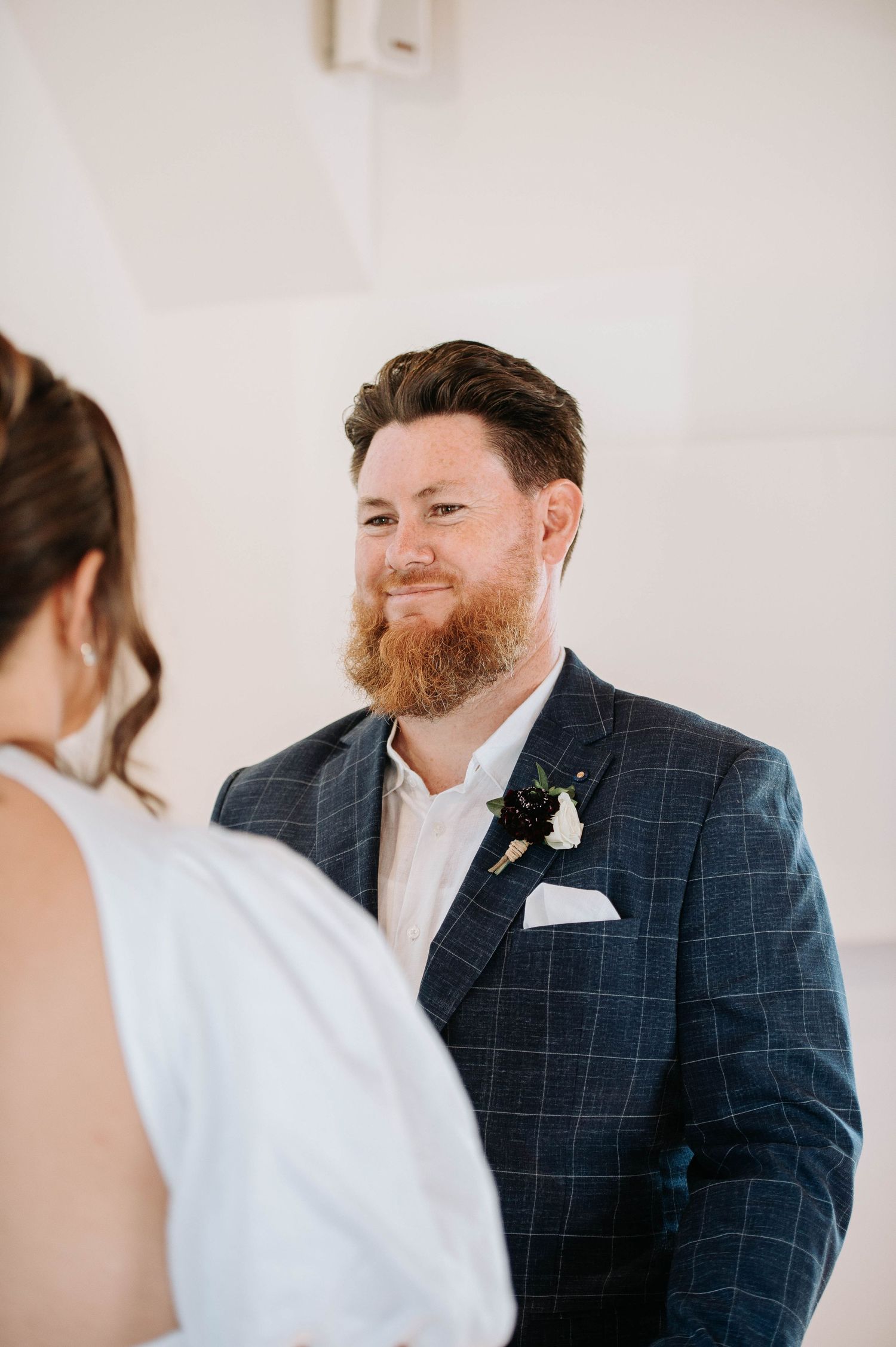 Groom in navy checkered suit during wedding ceremony.