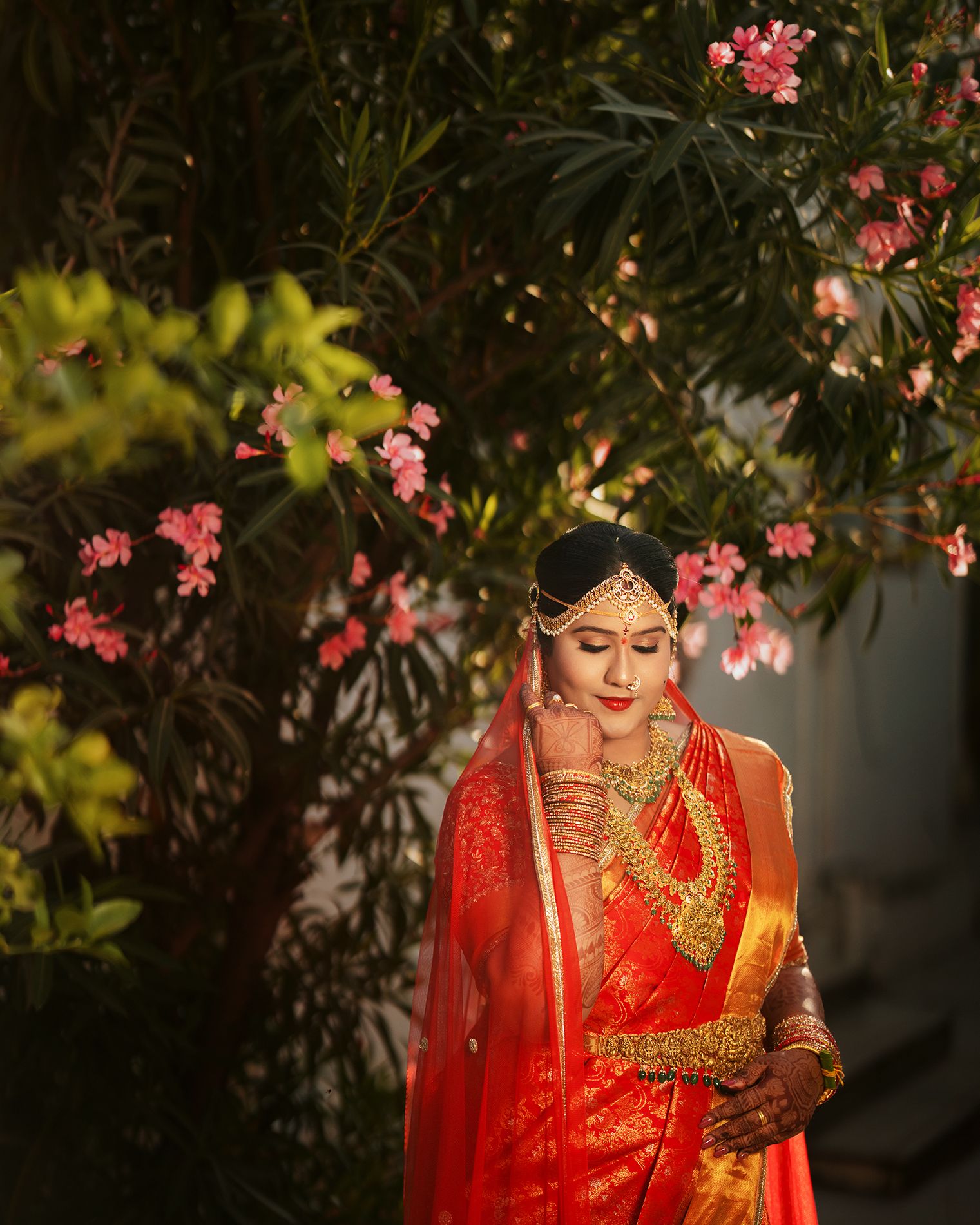 Traditional wedding ceremony moment beneath crystal chandelier and red roses.
