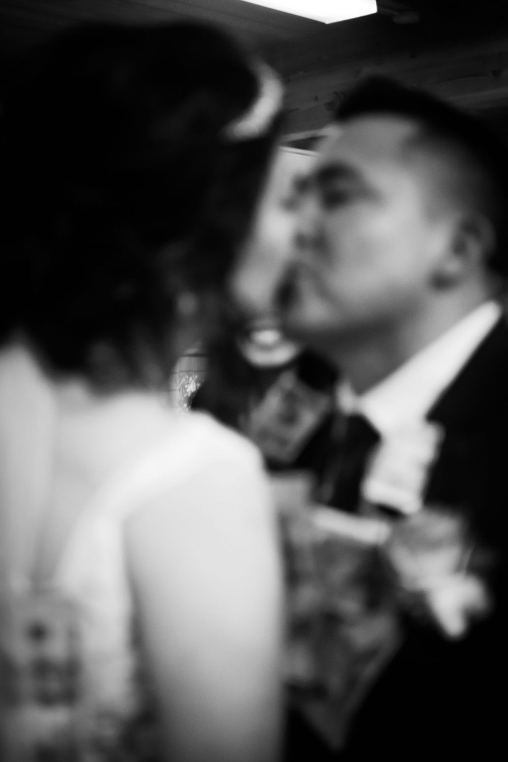 Artistic black and white photo of a romantic wedding couple about to kiss, with soft focus and bokeh effects.