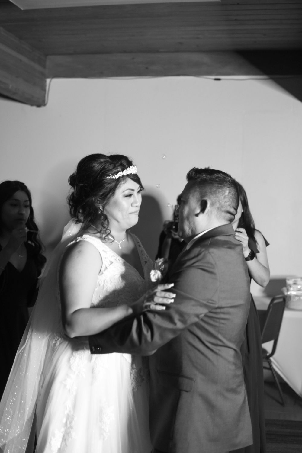 Black and white photo captures couple's emotional dance moment at wedding reception.